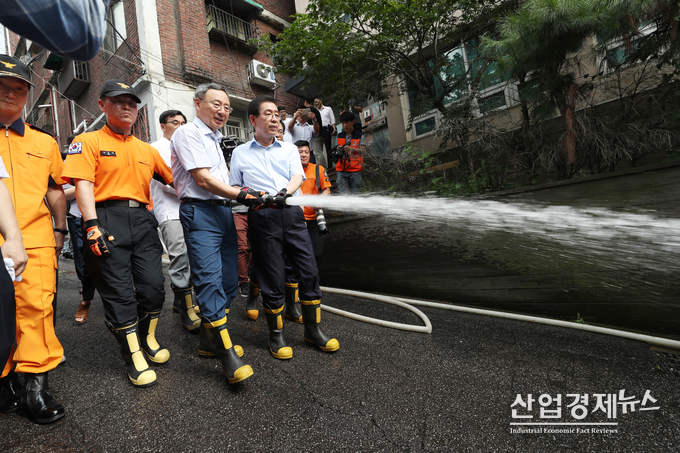 KT 황창규 회장과 박원순 서울시장이 용산소방서 대원들과 동자동 쪽방촌에 살수차로 물을 뿌리고 있다.