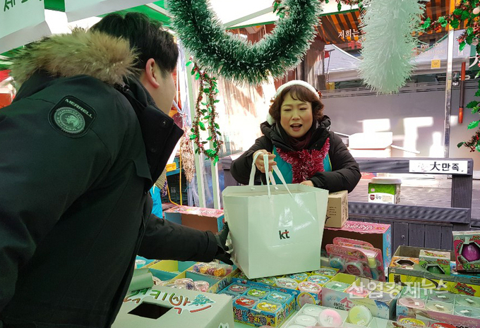 KT 직원이 15일 서울 서대문구 포방터시장에서 시장 상인에게 방한용 조끼와 방한용 앞치마를 전달하고 있다.