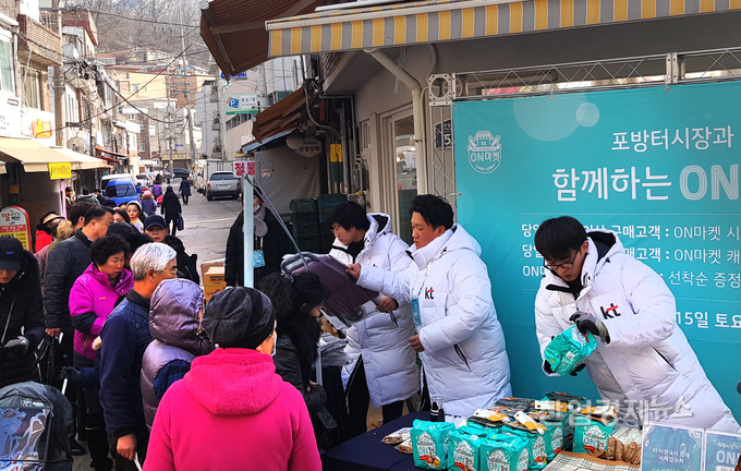 KT 직원이 15일 서울 서대문구 포방터시장에서 시장을 찾은 지역민들에게 장바구니, 온쫄면, 핫팩, 온음료 등을 나눠주고 있다.