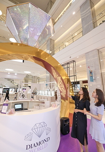 판교점 1층 열린광장에서 고객들이 4M 높이의 다이아몬드 반지 모형이 설치된 '골든듀 다이아몬드 월드' 팝업스토어를 구경하고 있다...현대백화점 제공