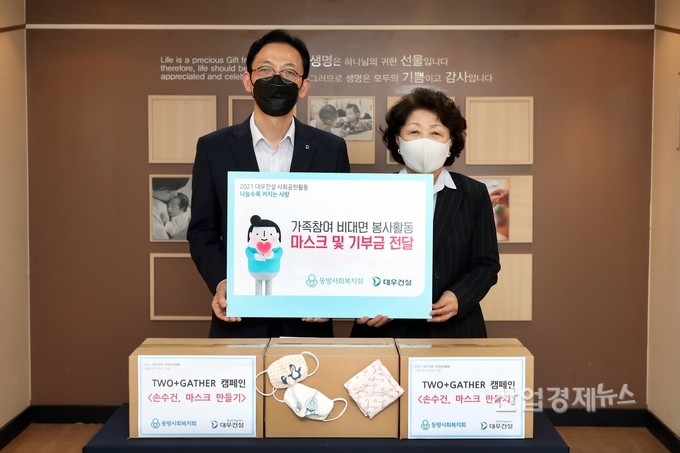 대우건설은 지난 2일 임직원과 가족이 참여해 제작한 마스크와 기부금을 동방사회복지회에 전달했다. 사진은 전달식에 참여한 강기남 대우건설 관리지원실장(왼쪽), 김진숙 동방사회복지회 회장의 모습. 사진=대우건설